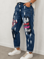Jean Amore S.Woman porté de trois quarts avec gros plan sur les inscriptions Amour multicolores et les effets peinture du denim