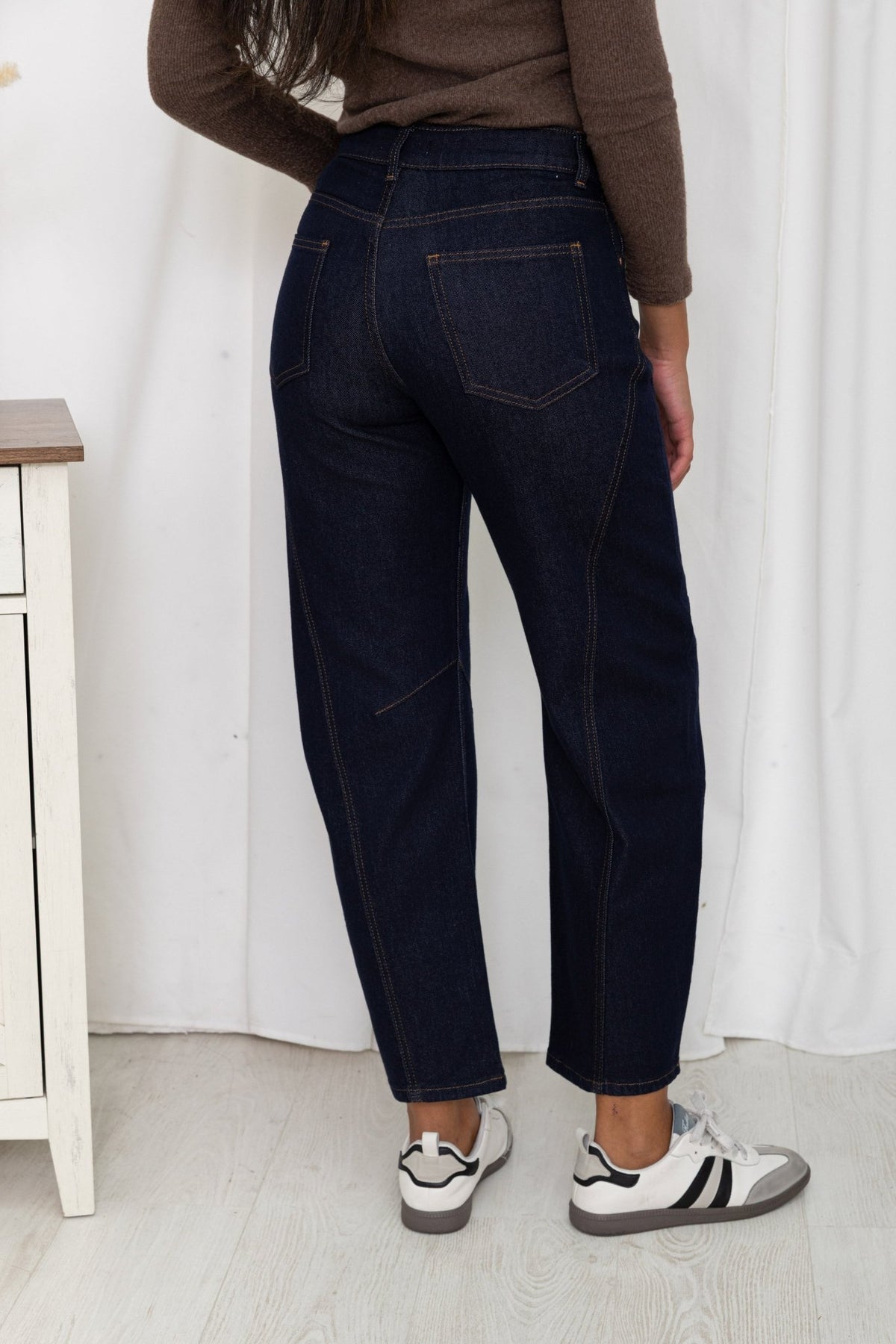 Jean barrel bleu brut porté de dos avec des baskets, vue de la taille aux pieds