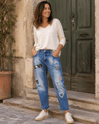 Femme portant le jean Brera S.Woman boyfriend délavé à strass devant une porte vert olive en Italie