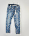 Jean floral femme coupe slim taille normale, délavage clair avec motif fleurs discrètes, vue bas du corps.