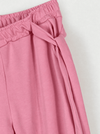 Gros plan de la taille élastiquée et du lien noué sur le côté du jogging rose poudré.
