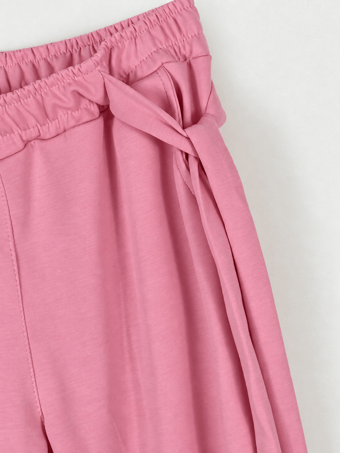Gros plan de la taille élastiquée et du lien noué sur le côté du jogging rose poudré.