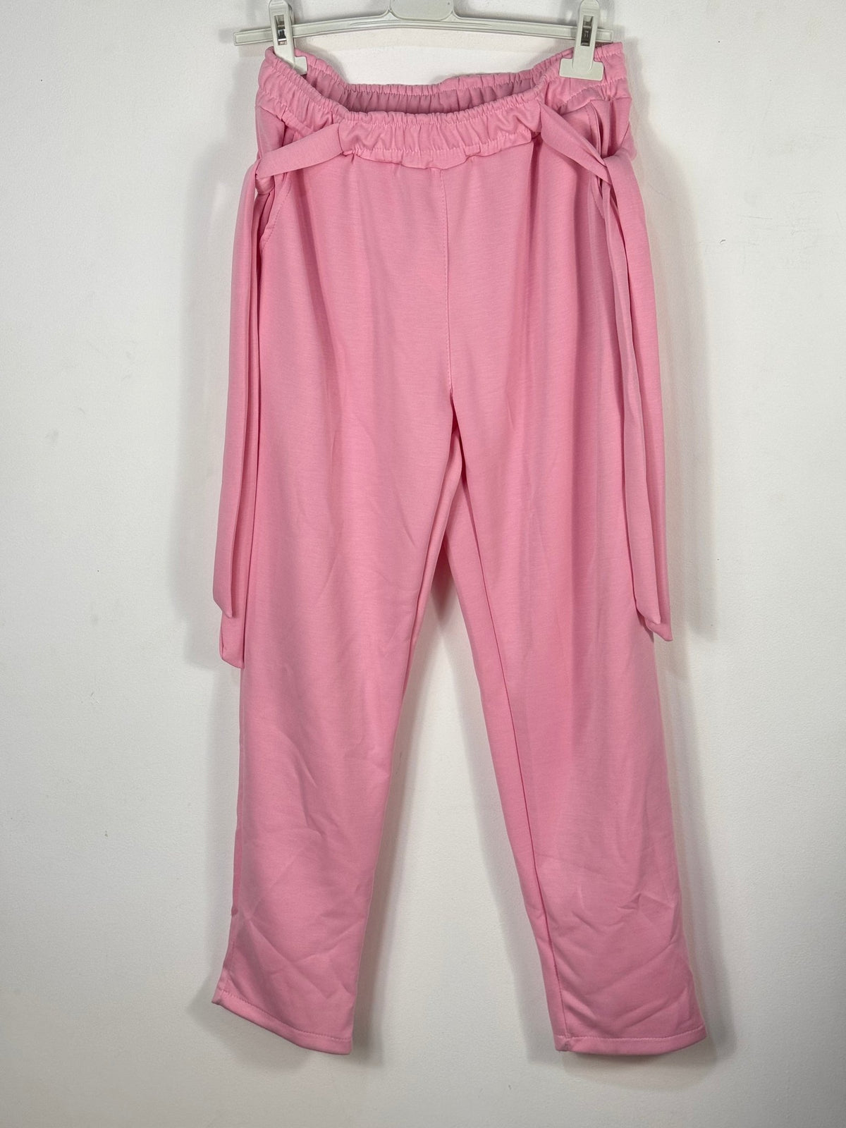 Jogging rose poudré sur cintre vu de face, taille élastiquée et liens latéraux.