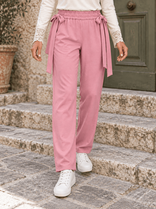 Jogging rose poudré porté, cadrage de la taille aux pieds montrant les nœuds latéraux et les jambes fuselées.