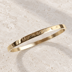 Bracelet jonc Mamie en or – Acier inoxydable doré sur pierre claire, vue du bijou retouchée.