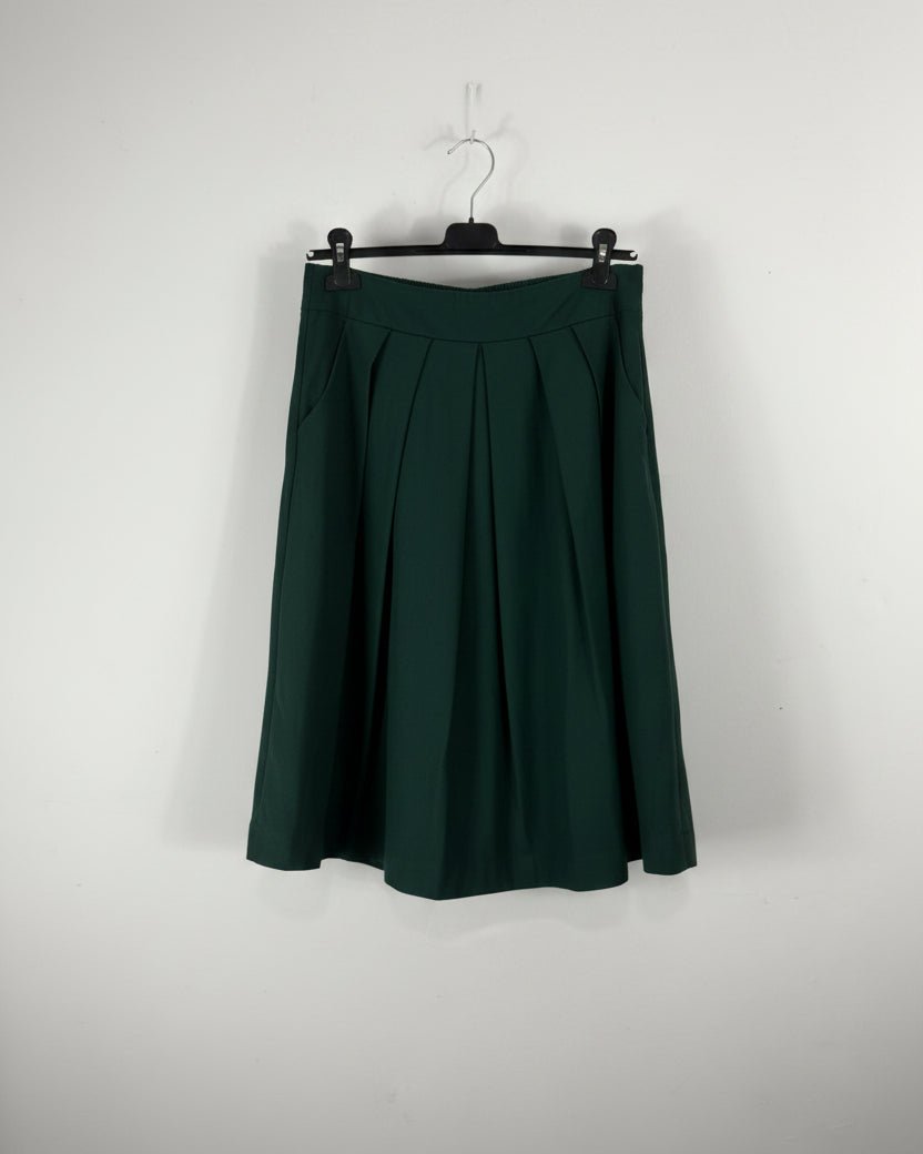 Jupe plissée mi-longue vert forêt sur cintre, silhouette ample et élégante pour l'automne