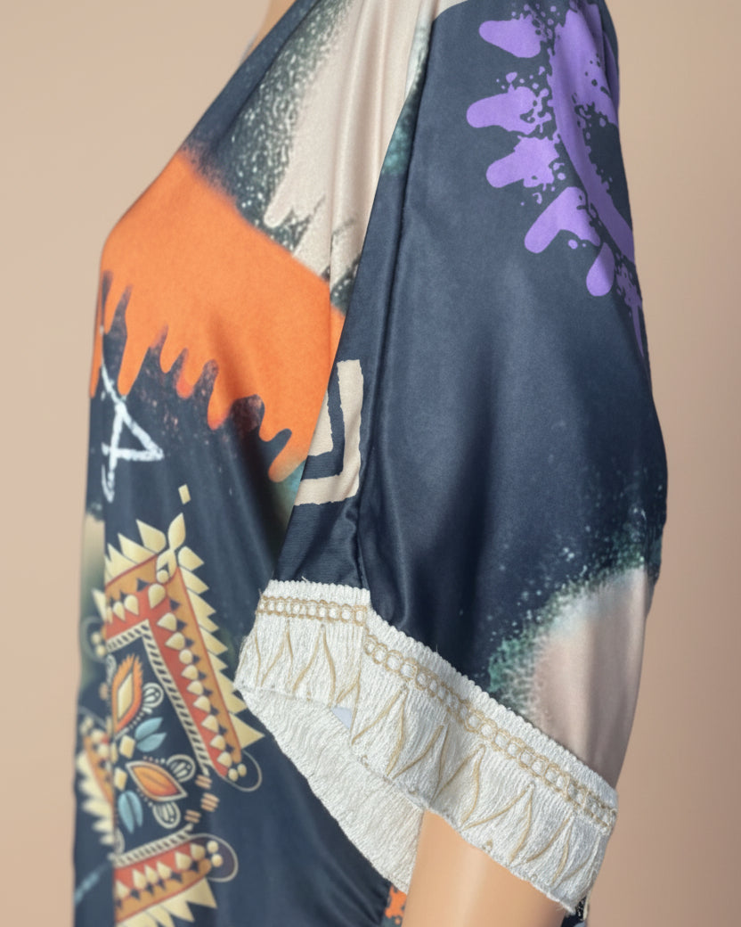 Détail de la manche du kimono bohème : bordure en dentelle blanche et franges sur tissu satiné à imprimé ethnique orange et marine