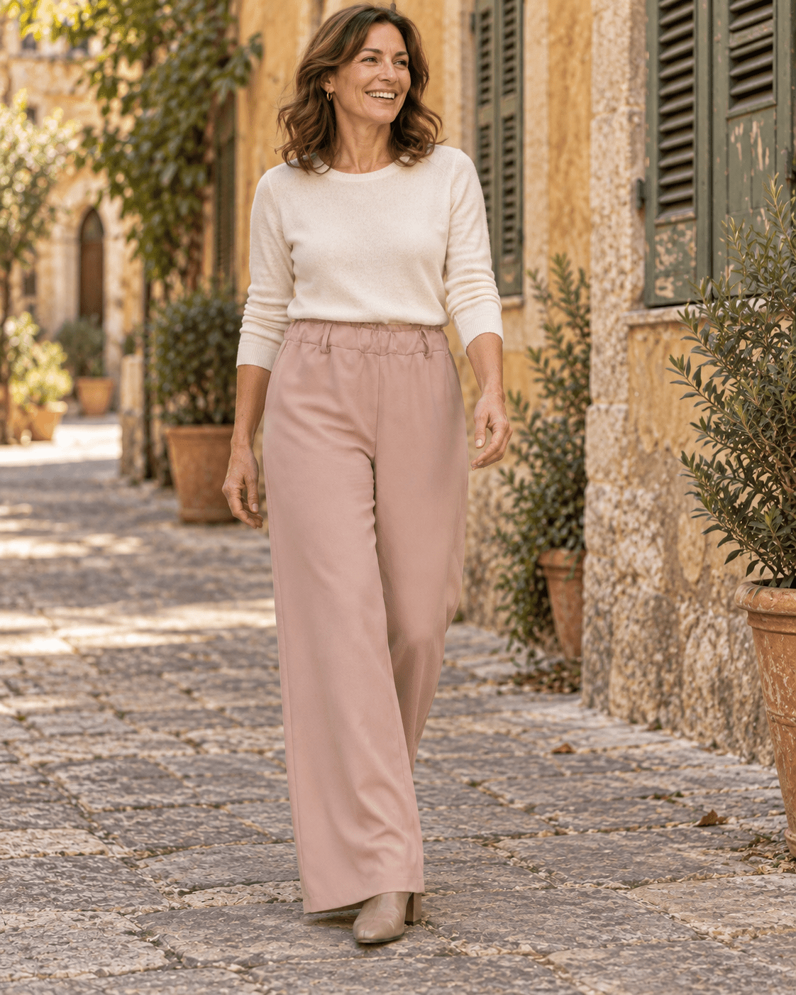 Pantalon chino rose poudré en silhouette entière avec un pull ivoire et des bottines