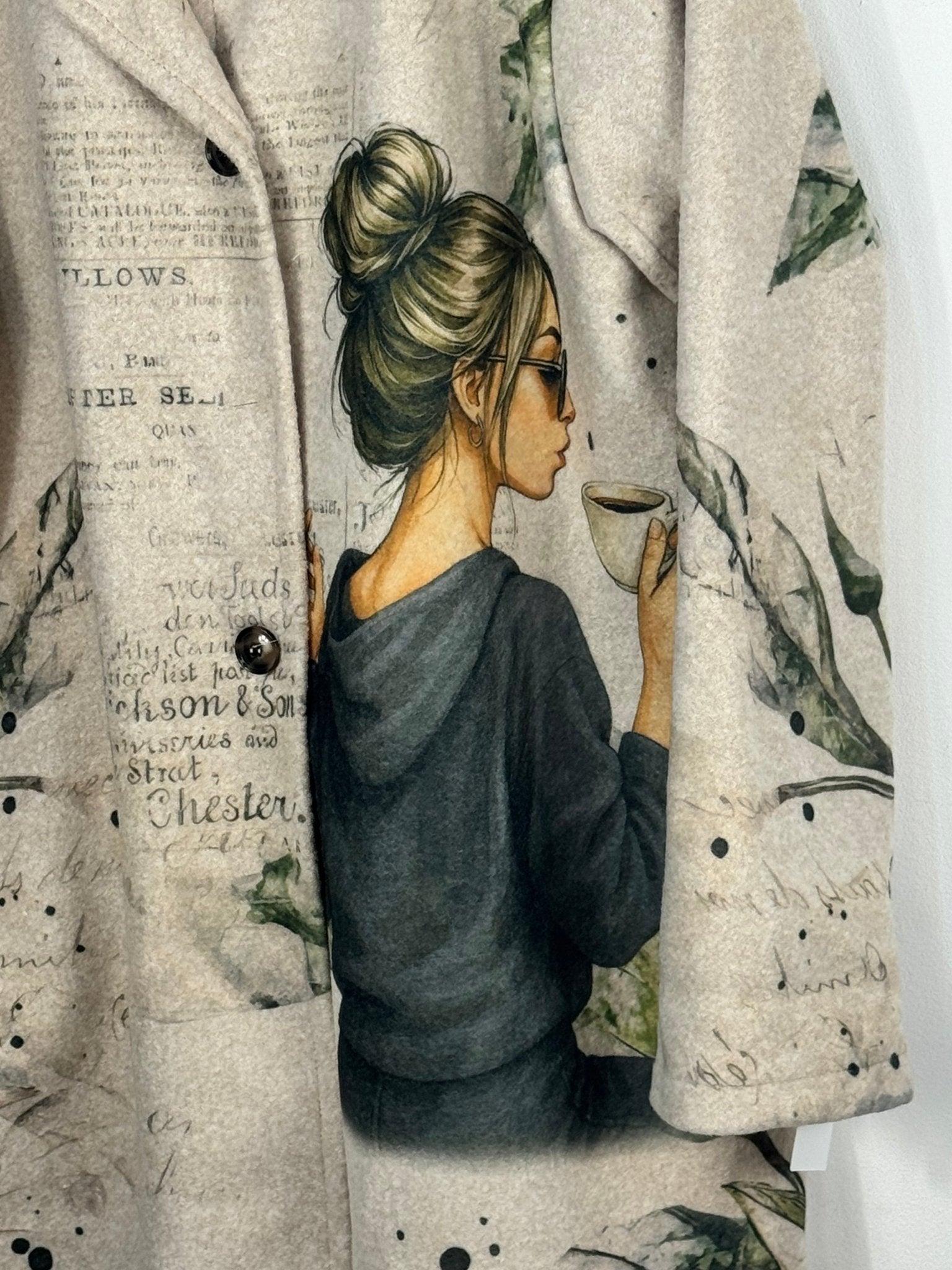 Détail réel du manteau Paola, illustration femme au café, écritures vintage et boutons