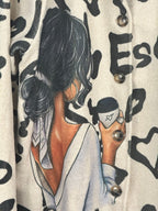 Détail réel du manteau Valentina, illustration femme au café, boutons et imprimé graphique noir