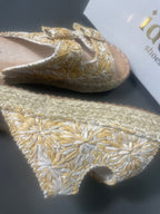 Détail du tissu brodé des mules espadrilles bohèmes : motifs floraux en fils dorés et blancs sur fond écru, finition surpiquée