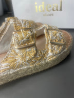 Gros plan sur les deux boucles carrées dorées des mules espadrilles bohèmes à broderies florales écru et or