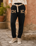 Femme portant le Pantajog Chic noir avec détails léopard, strass et ceinture dorée dans une ambiance italienne