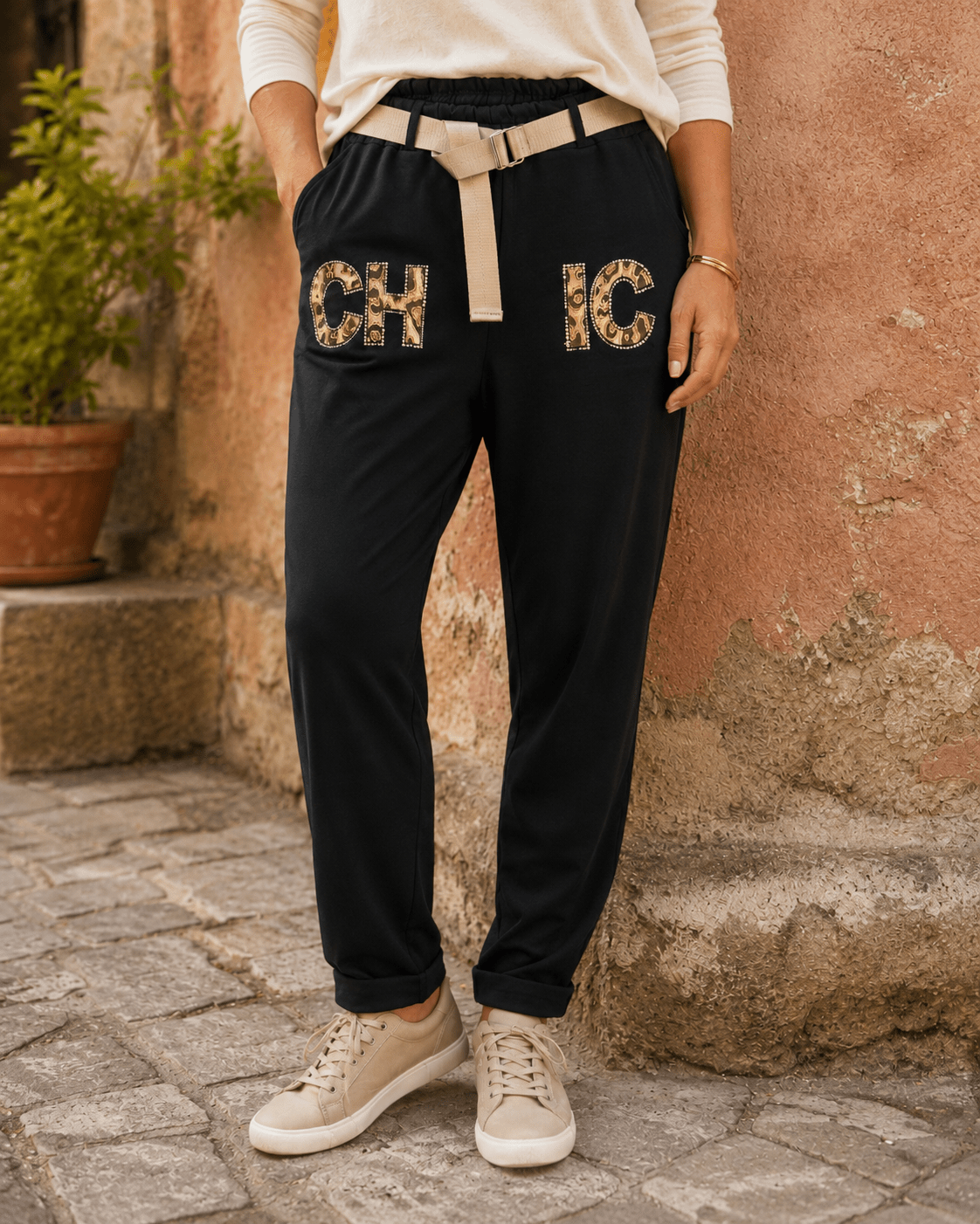 Femme portant le Pantajog Chic noir avec détails léopard, strass et ceinture dorée dans une ambiance italienne