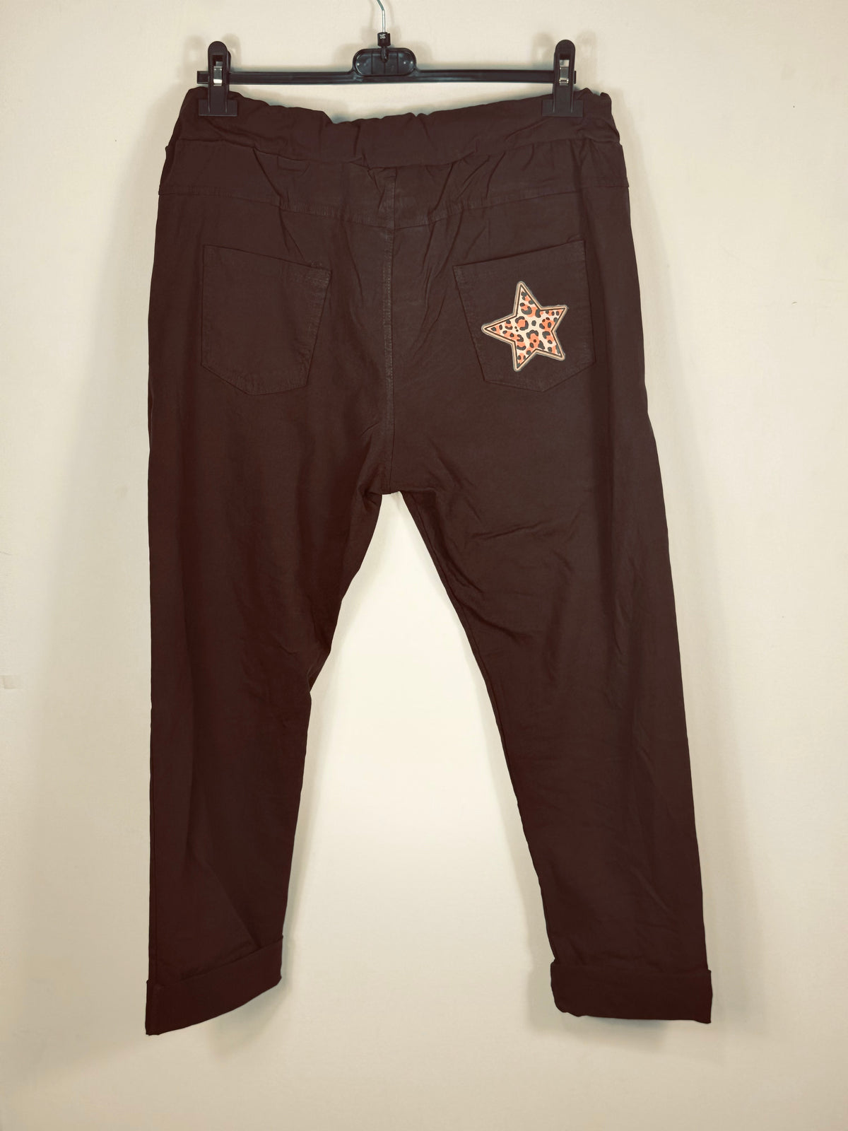 Pantalon magique Étoile chocolat de dos sur cintre, avec deux poches plaquées et une étoile léopard.