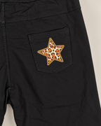 Détail retouché de la photo boutique : étoile léopard orange et noire sur la poche arrière du pantalon noir.