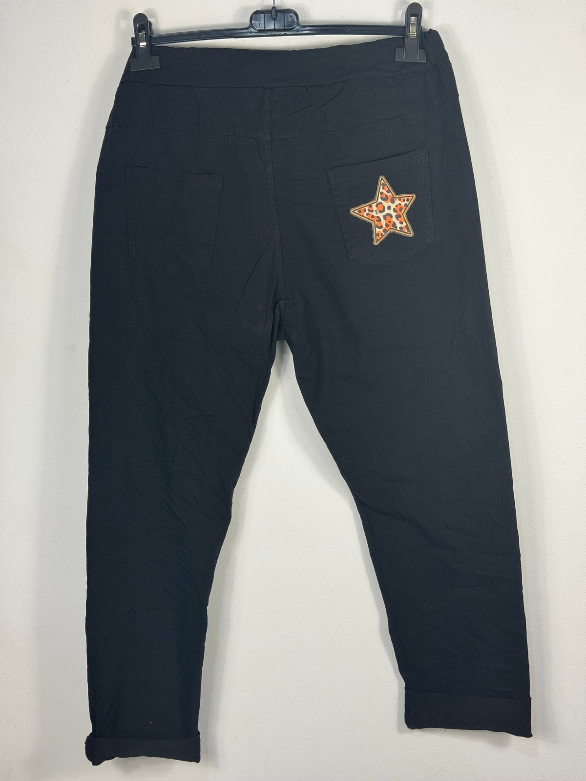 Dos du pantalon magique Étoile noir sur cintre, deux poches arrière dont celle de droite ornée d’une étoile léopard.