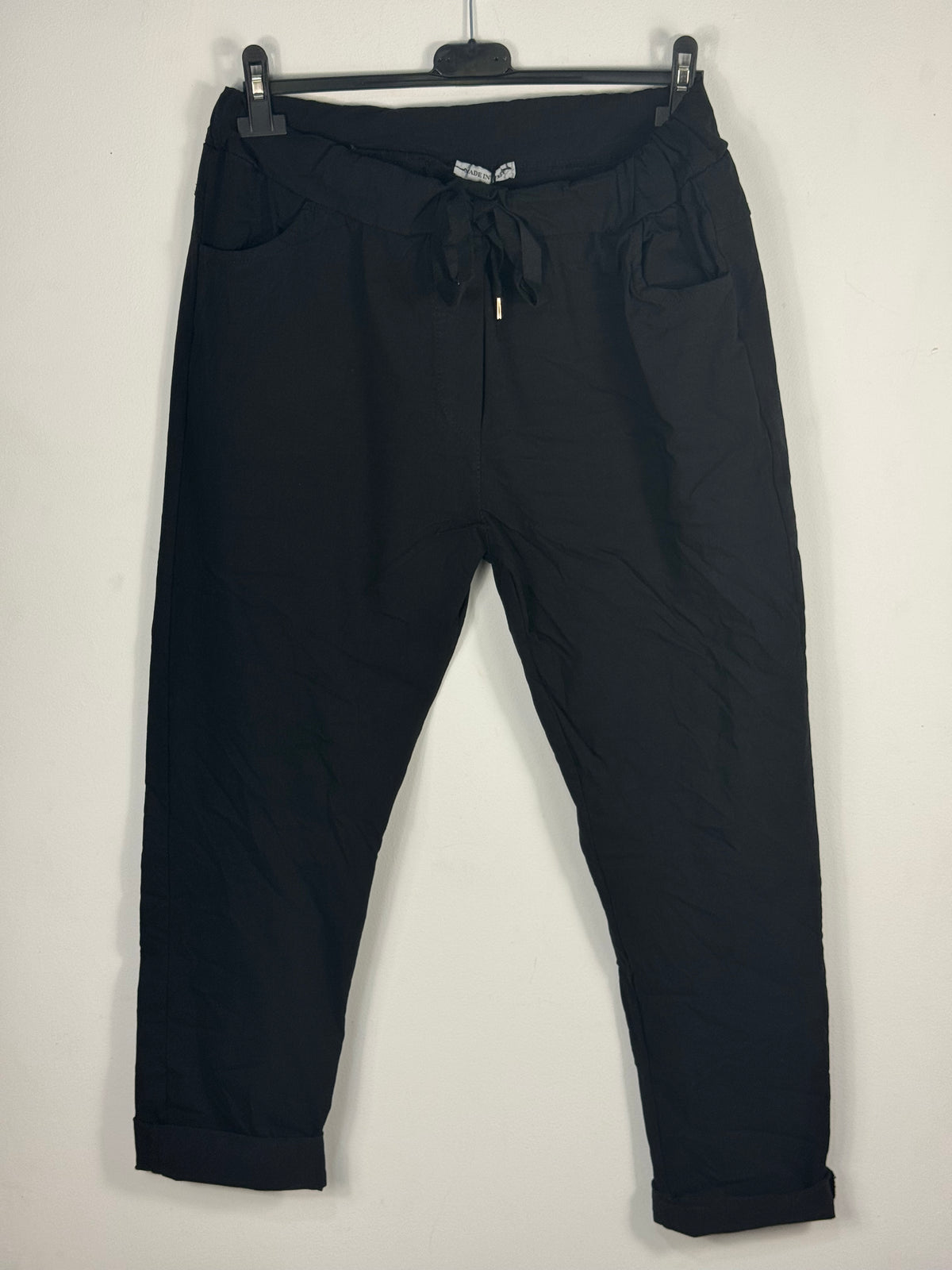 Pantalon magique Étoile noir sur cintre, vue de face avec ceinture élastiquée, lien et deux poches.