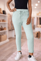 Look du jour : pantalon fluide grande taille vert d'eau, silhouette mise en valeur, ambiance boutique moderne en arrière-plan