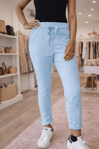 Tenue casual pour femme ronde : pantalon bleu ciel extensible, coupe droite et revers, mis en scène dans une boutique tendance.