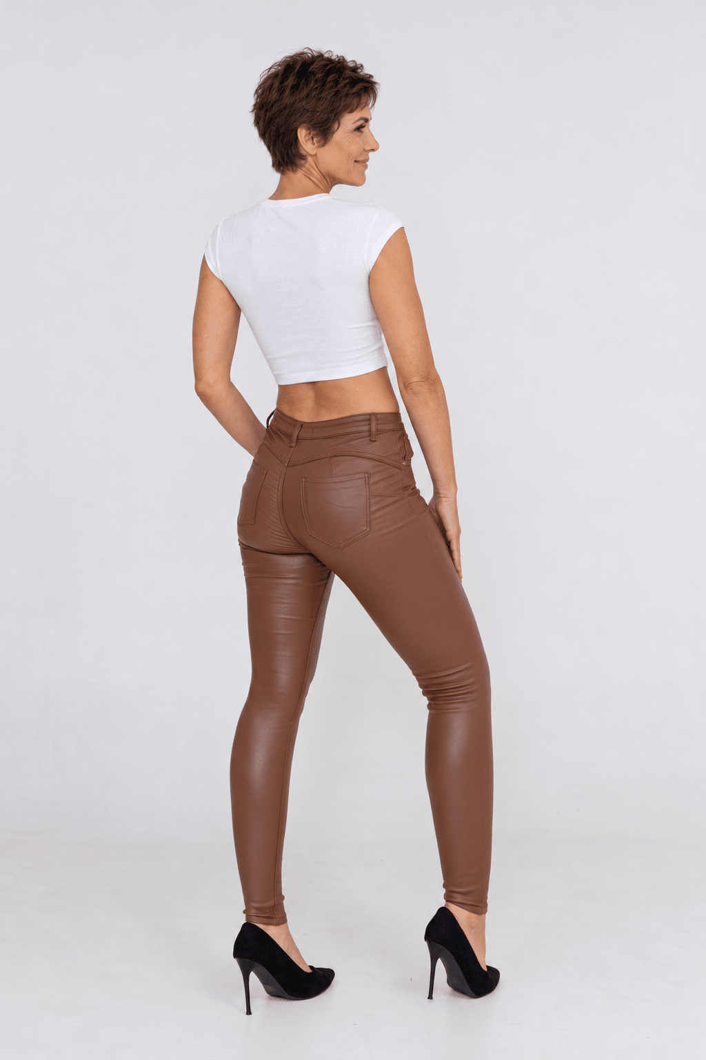 Sofia portant le pantalon ajusté en simili chocolat, vue dos.