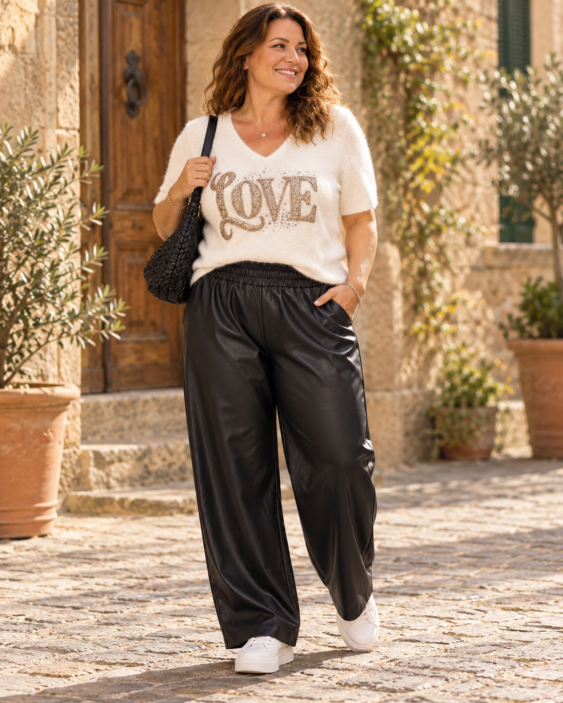 Pantalon simili noir grande taille porté par Eva avec un pull Love