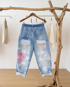 Pantalon femme jean clair patchwork – vue de dos sur cintre avec détails imprimés et coupe fluide