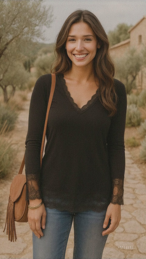 Modèle portant un rouleau sous-pull à manches longues blanc avec dentelle délicate au col et aux manches, associée à un jean bleu et un sac à main en cuir marron, souriant dans un cadre boho naturel.