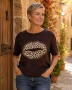 Femme portant le pull Bacio chocolat à bouche léopard et strass avec un jean dans une ambiance italienne