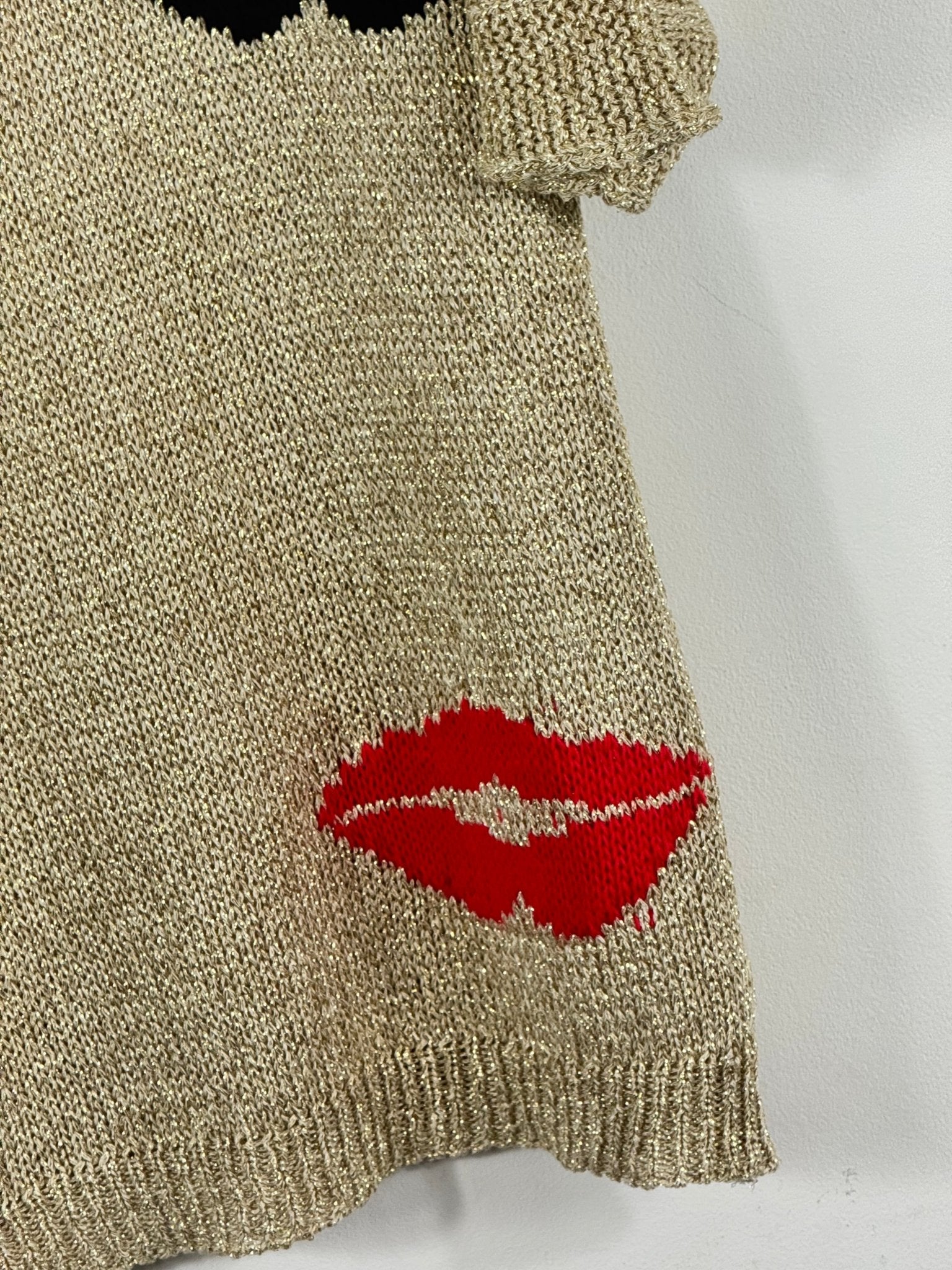 Détail réel de la bouche rouge et des fils brillants dorés du pull Bella