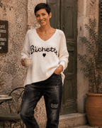 Pull Bichette écru porté avec pantalon noir devant une terrasse italienne