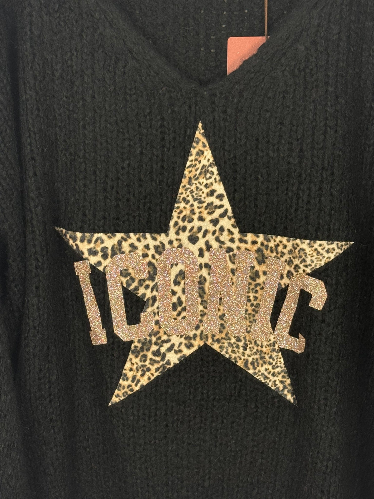 Détail du motif léopard et des lettres scintillantes sur le pull Iconic noir