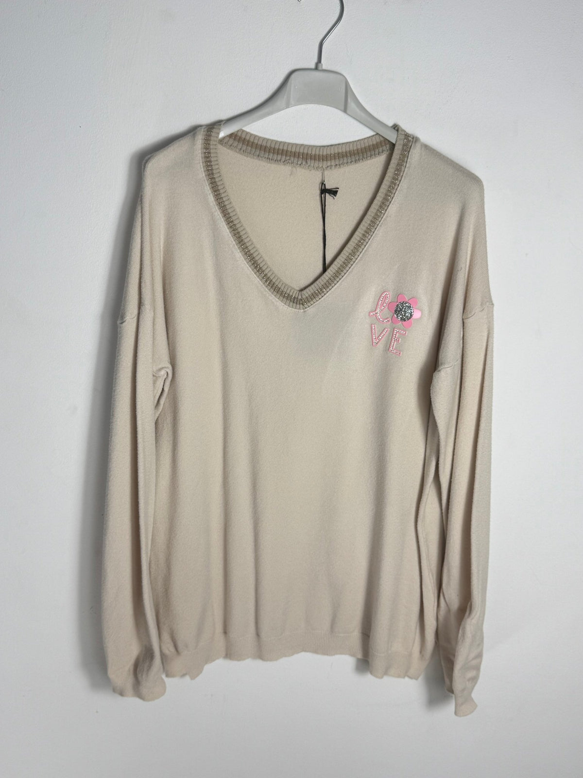 Pull Lucia beige sur cintre, col V à liseré brillant et motif LOVE côté cœur.