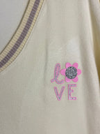 Gros plan du motif LOVE rose, de la fleur et des strass du pull Lucia.