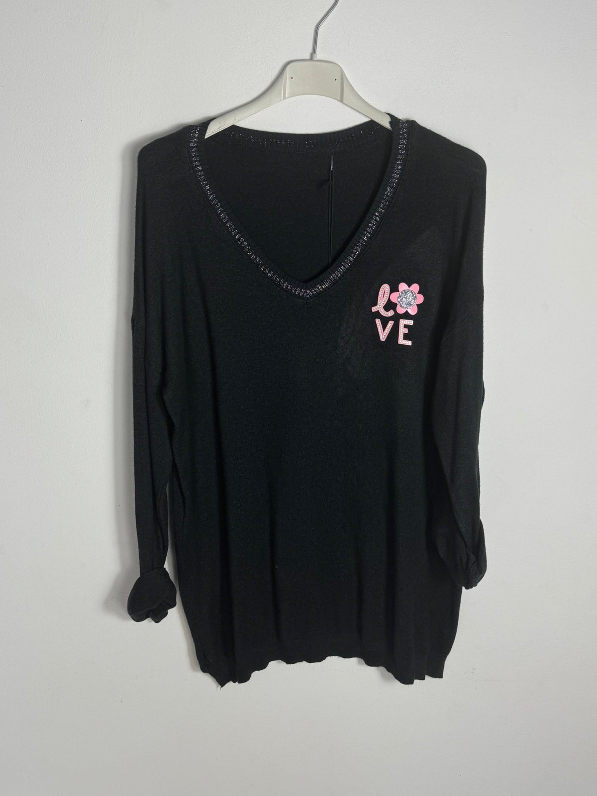 Pull Lucia noir sur cintre, petit motif LOVE rose et col V à liseré brillant.