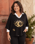Femme portant le pull Occhio noir à motif œil pailleté sur une chemise blanche devant une porte terracotta en Italie