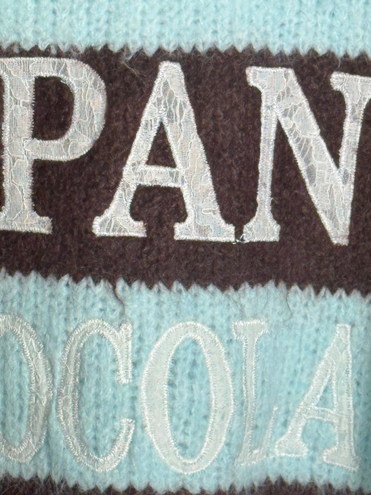 Détail de l’inscription en dentelle du pull PAN CHOCOLATE bleu ciel