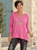 Pull Stella rose bonbon porté avec le jean Milano noir, col V et motif Rock & Peace à strass. (Mise en scène IA.)