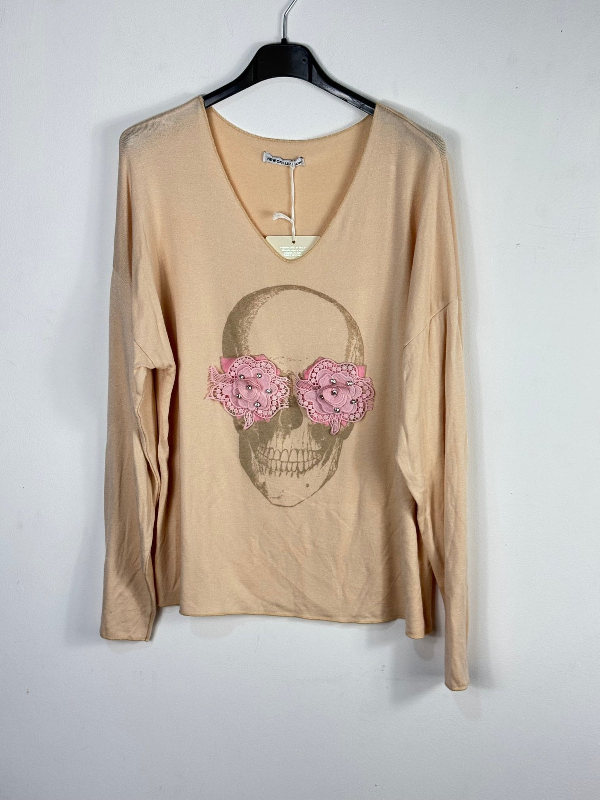 Photo source du pull dans une nuance beige chaude, avec tête de mort dorée et fleurs roses.