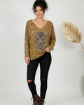 Femme portant un pull moutarde à tête de mort scintillante, manches longues, style rock chic