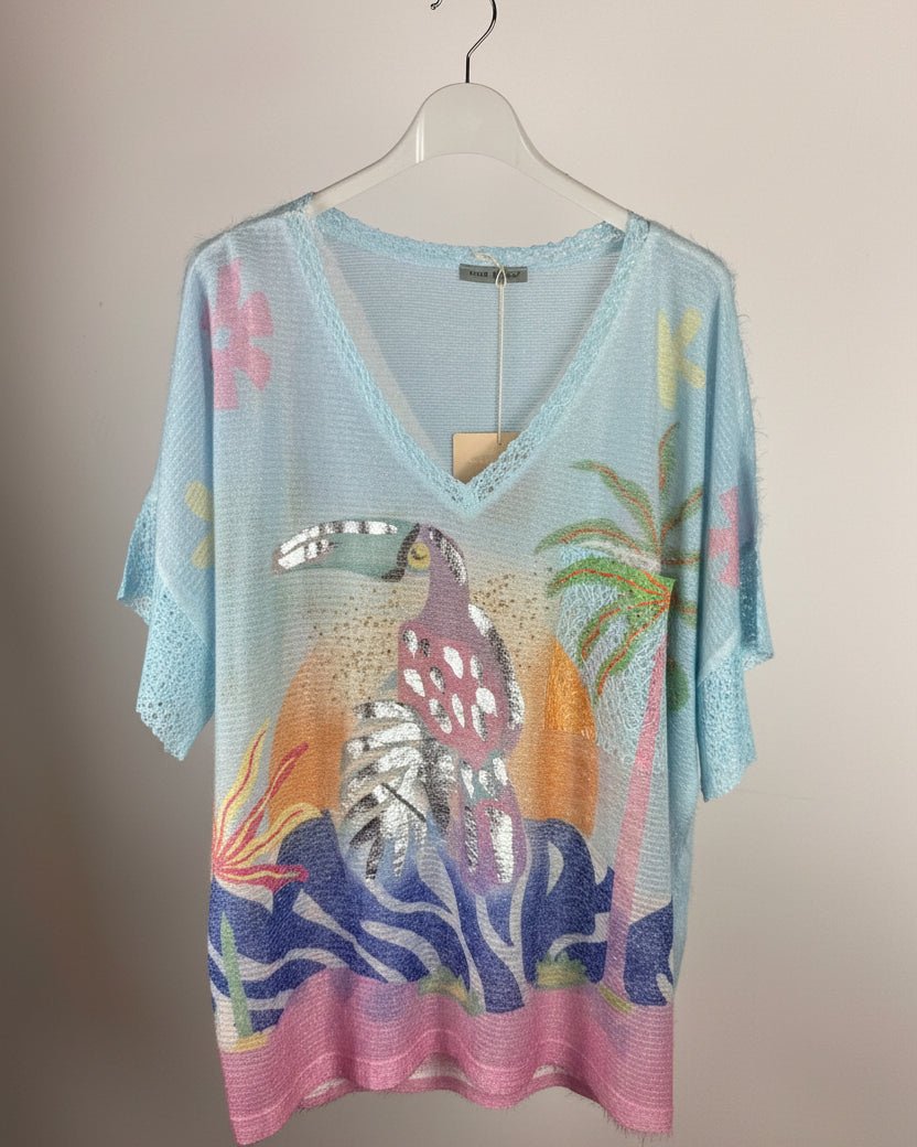 Pull femme bleu ciel en maille pailletée avec grand toucan tropical coloré sur le devant, vue de face