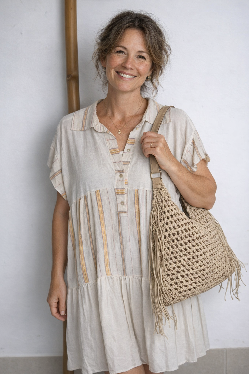 Robe bohème courte écrue à broderies dorées et col polo, portée avec un sac hobo en crochet naturel à franges
