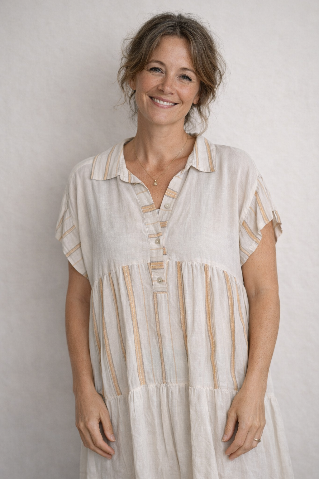 Robe courte bohème écrue à rayures dorées et col chemise, coupe babydoll à volants, portée naturellement
