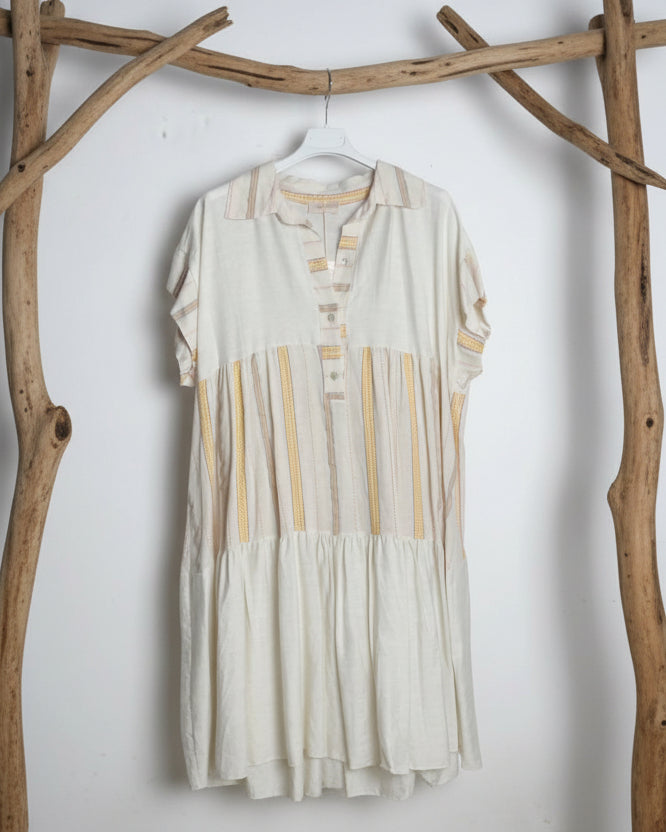 Robe courte bohème en lin écru avec rayures brodées dorées et jaunes, col chemise, coupe babydoll à volants étagés, vue de face