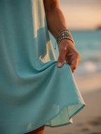 Détail tombé fluide de la robe turquoise manches volantées, main qui relève le tissu – Mam's Ailes
