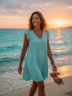 Femme portant la robe fluide manches volantées turquoise sur la plage au coucher de soleil – Mam's Ailes