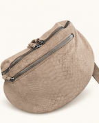 Sac Serpente beige, gros plan du motif serpent et des zips argentés, photo retouchée sur fond clair.