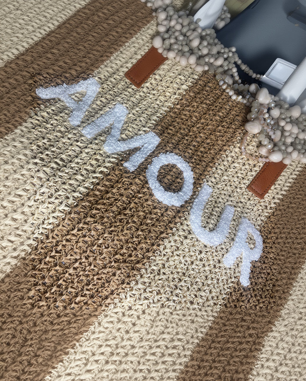Détail inscription AMOUR moumoute blanche sur sac cabas paille tressée beige camel