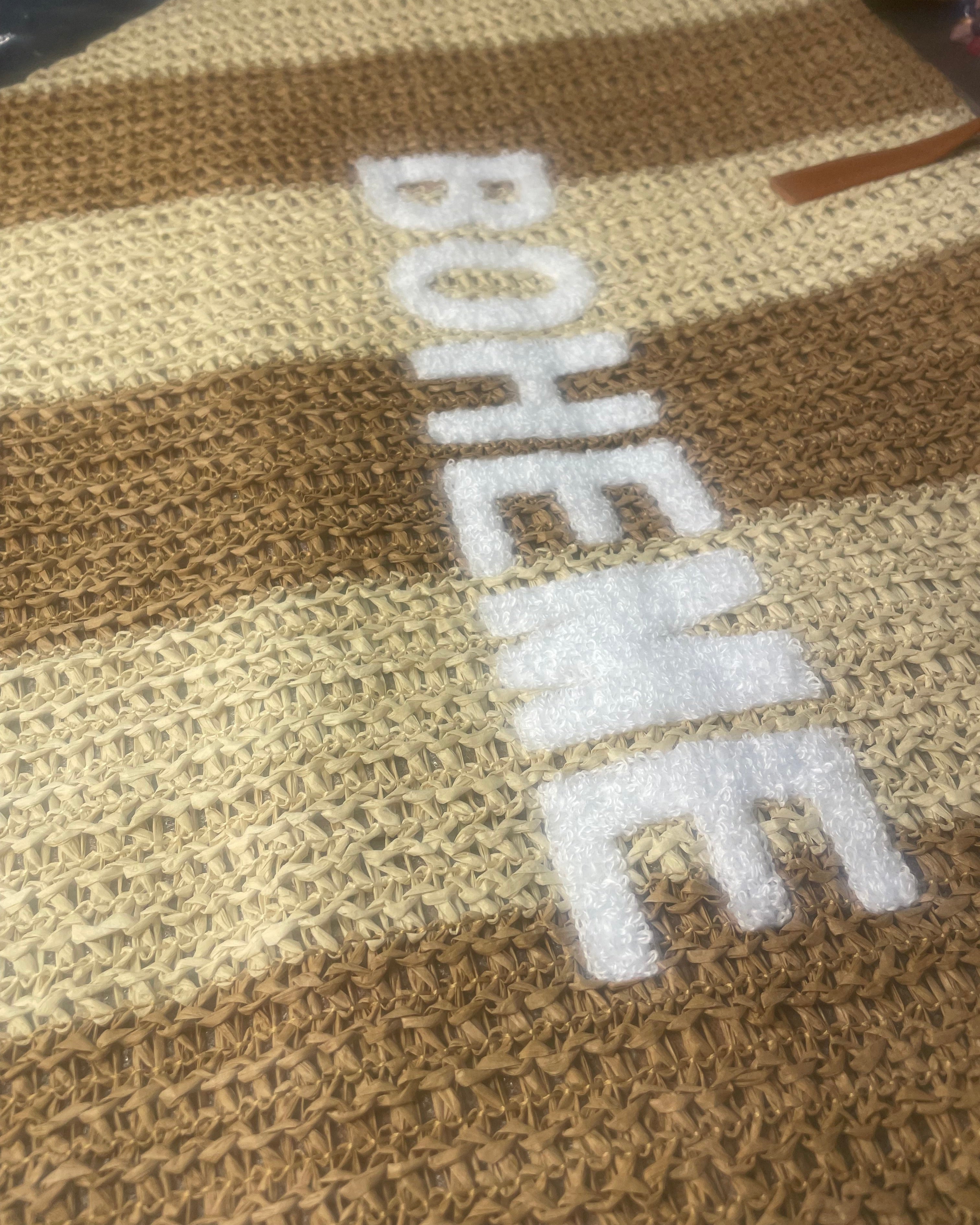 Détail inscription BOHEME moumoute blanche sur sac cabas paille tressée beige camel