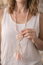 Femme portant un sautoir bohème long avec pendentif cœur et pompons